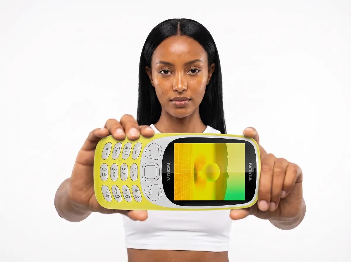 Model holding the yellow Nokia 3210 towards the camera